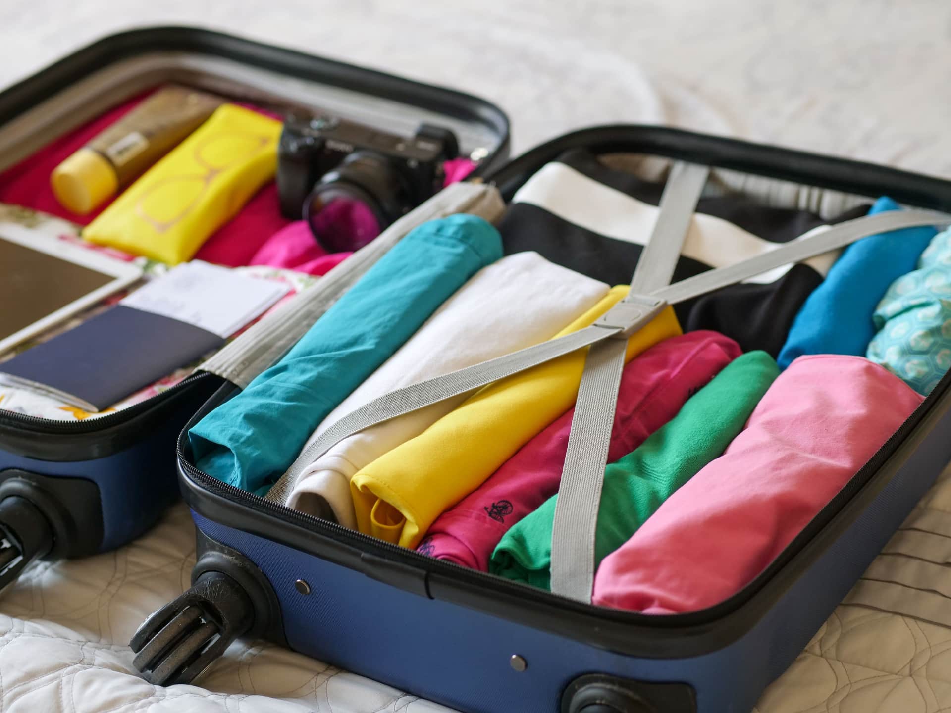 An open carry-on packed with rolled clothes in packing cubes